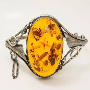 Vintage Hinged Bracelet in Silver and Baltic Amber: This vintage hinged cuff bracelet features an oval Baltic amber cabochon with sterling silver scroll work surrounding it. Inside measurement 6.25". Amber measures 36.6mm x 21.9mm. Weight 0.75ozt.