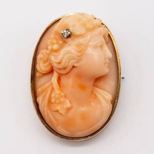 Pink Coral Cameo Brooch Pendant with Diamond Accent: This pink coral cameo of a woman is bezel set in 14K yellow gold and features one round diamond accent. 1 1/8" x 7/8". Diamond is approximately 0.01ct. Weighs 6.7dwt.