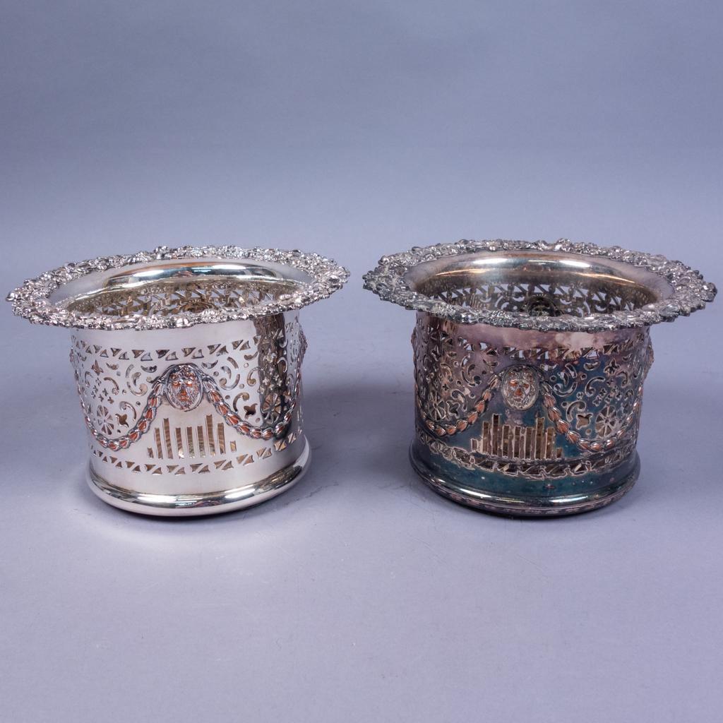Antique Pair Sheffield Silver SP Magnum Wine Coasters: This is an antique pair of English Sheffield Silverplated magnum wine coasters dating to the 19th century. The pierced set features flowers and lion head garland. Wooden bases. Plated over copper. The