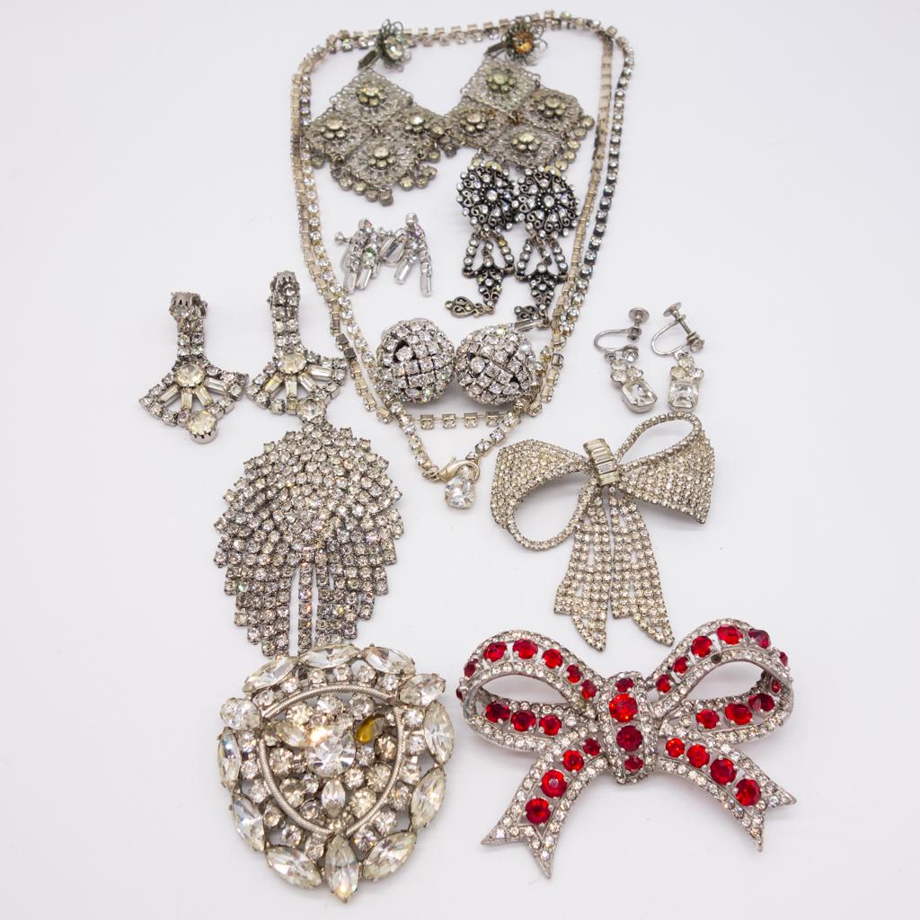 Vintage Lot Rhinestone Jewelry incl Earrings, Pins: This is a vintage lot of ladies fashion jewelry each with silver tone settings encrusted with sparkling rhinestones. The bow brooch with the red stones is 3 x 2".