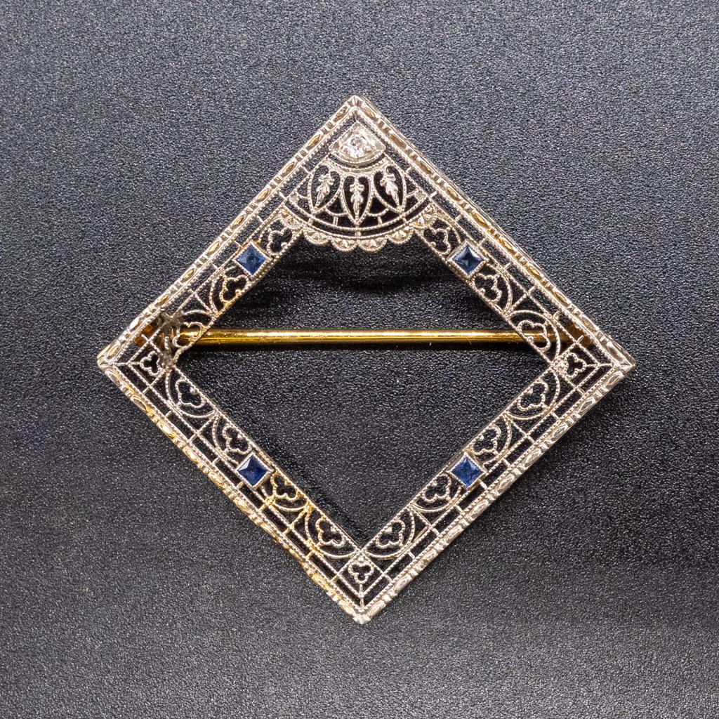 Art Deco 14K Gold Filigree Diamond Sapphire Brooch: This is a vintage brooch pin dating to the 1920s. Rendered in fine 14k white and yellow gold, this Art Deco filigree brooch features vibrant blue sapphires and an Old Mine cut diamond adorning the cen