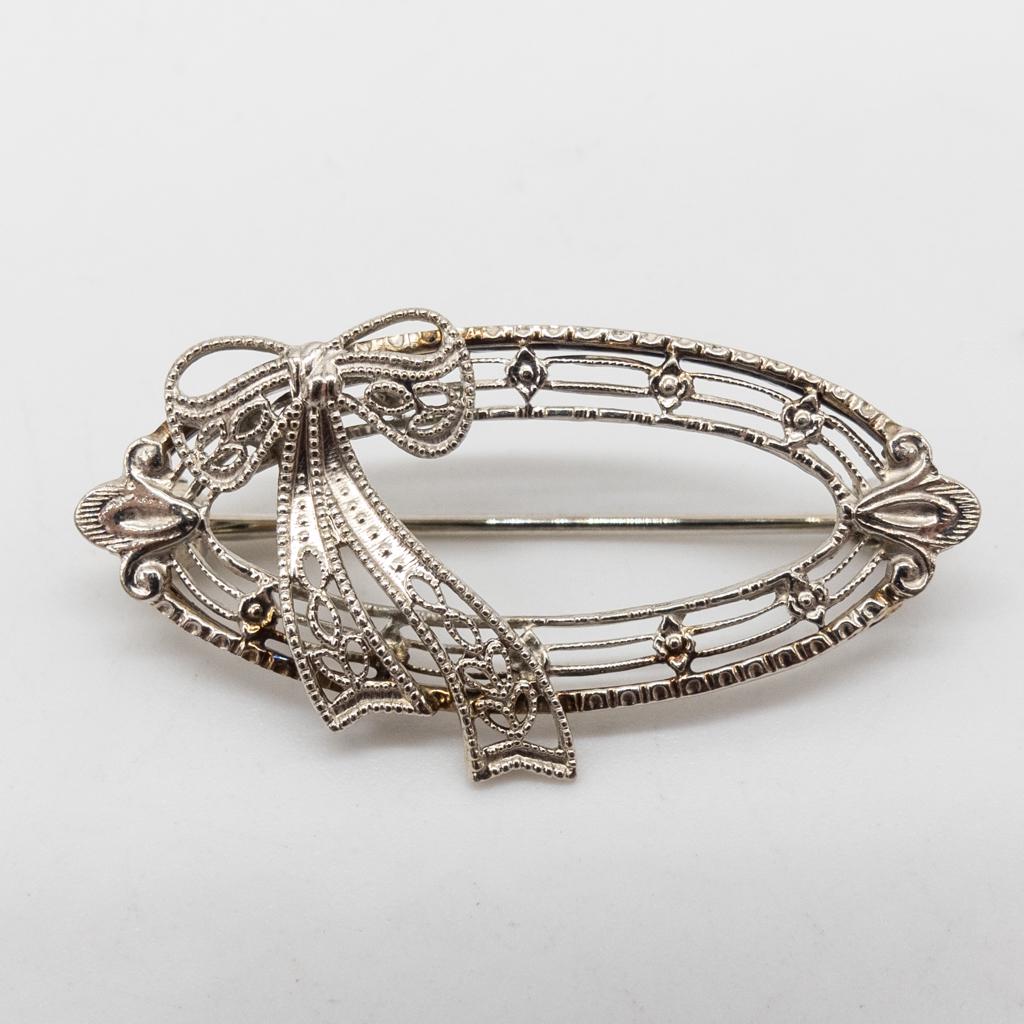 Antique Art Deco Solid White Gold Filigree Bow Brooch: This is an antique Art Deco 10K white gold filigree bow motif brooch pin dating to the 1920s. 1 1/8 x 5/8". It weighs a total of 1.8g.