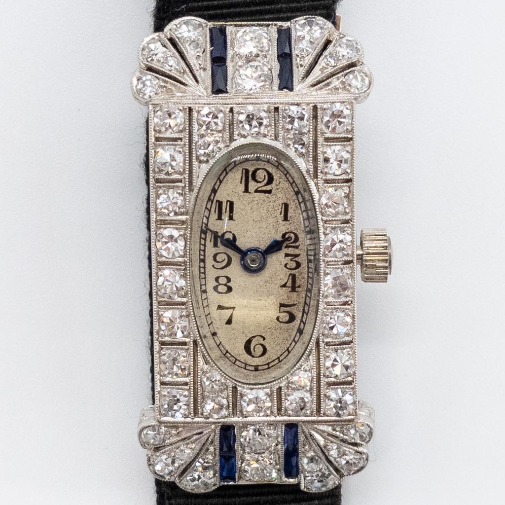 Platinum Diamond Sapphire Art Deco Ladies Wristwatch: This is an antique Continental European ladies wristwatch dating to the early 20th century. Rendered in fine platinum, this Art Deco watch is studded with full and single cut diamonds. VS clarity and 