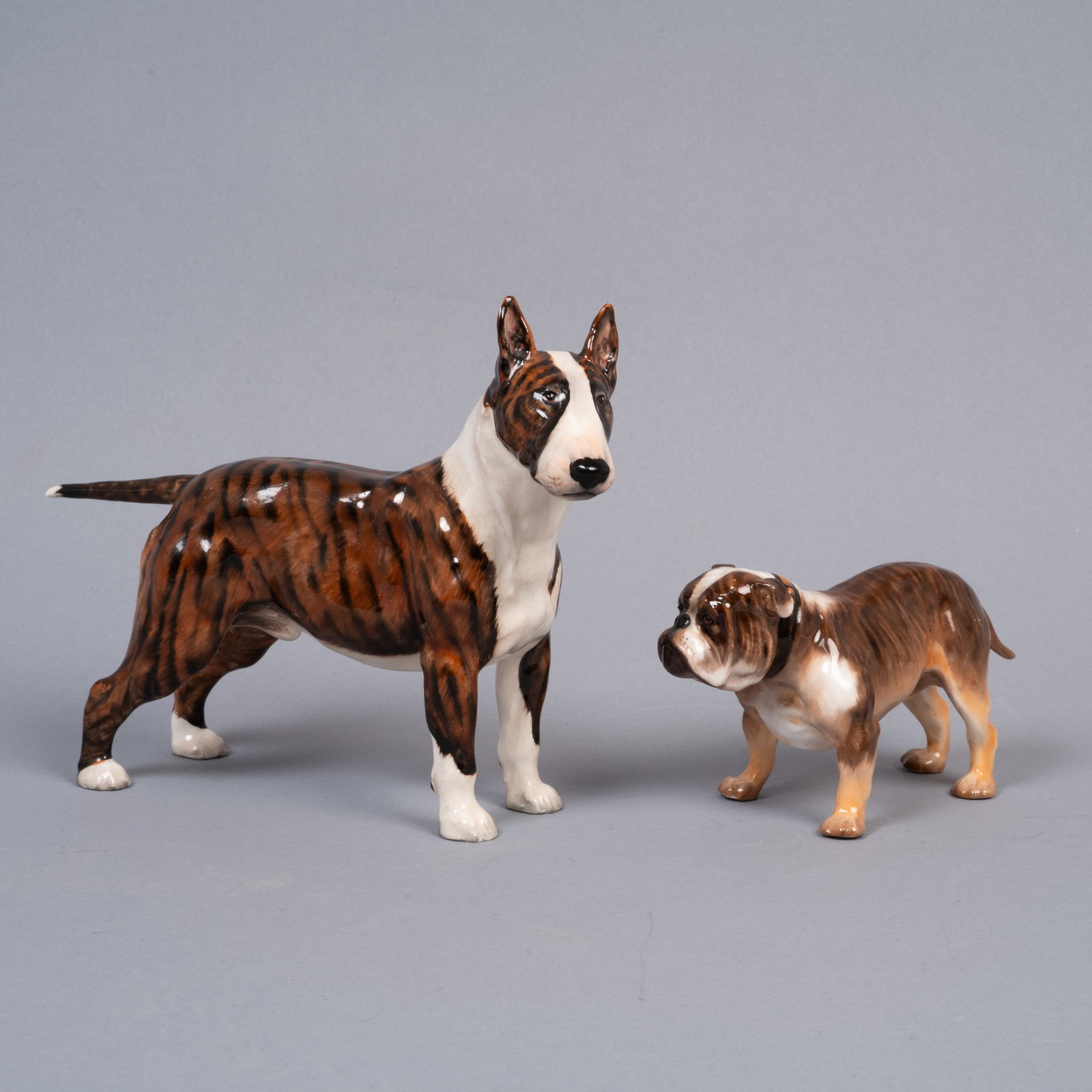 Pair of Royal Doulton Bone China Dog Figurines: Brindle Bull Terrier (HN1143) and Bulldog (HN1047): Lot 276 Pair of Royal Doulton Bone China Dog Figurines: Brindle Bull Terrier (HN1143) and Bulldog (HN1047) Description: A matched pair of vintage English bone china dog figurines by Royal Doulton: Bul