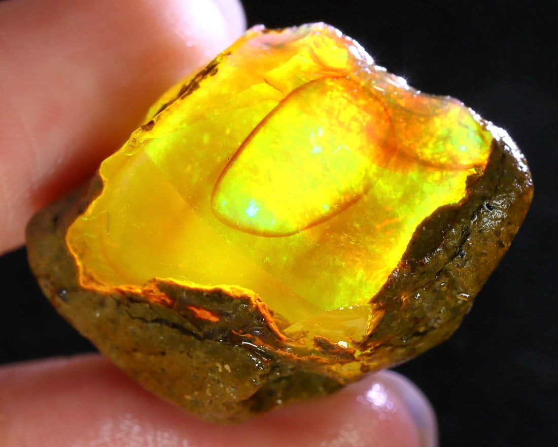 55Ct Captured Cosmos: Ethiopian Opal's Dazzling Display: Dimension: 30x22x16mm Raw Gemstone Specimens - Natural Rough Opal Hailing from the coveted mines of Delanta, Ethiopia, this opal specimen is a brilliant display of nature's artistry. Its vibrant play-