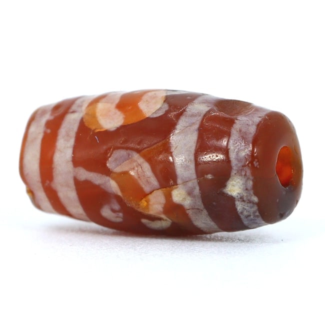 Ancient Etched Carnelian Bead: A Testament to Ancient Artistry (2000-1000BC): Dimension: 10.5x5.3mm Rarity Level: Extremely Rare This bead, with its advanced age, intricate etchings, and association with ancient civilizations, represents a period of impeccable artistry and cult