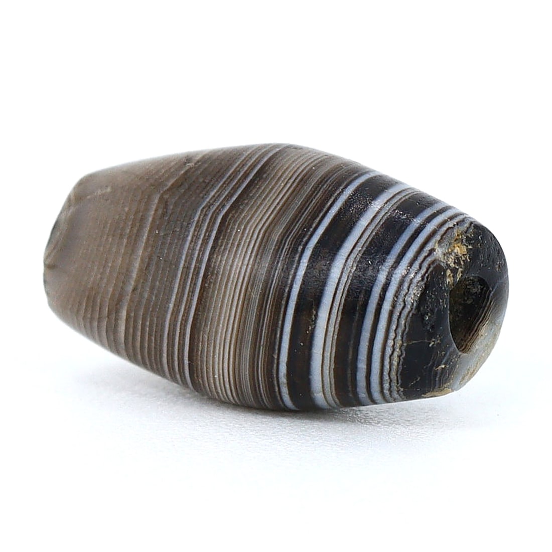Ancient Sulemani Banded Agate Dzi Bead: Himalayan Tibetan Elegance (700 BC-500 BC): Dimension: 10.4x6mm Rarity Level: Highly Rare Sourced from the Himalayan regions of Pakistan, this Sulemani banded agate bead speaks volumes about the artistry of its makers. Its distinctive Dzi patte