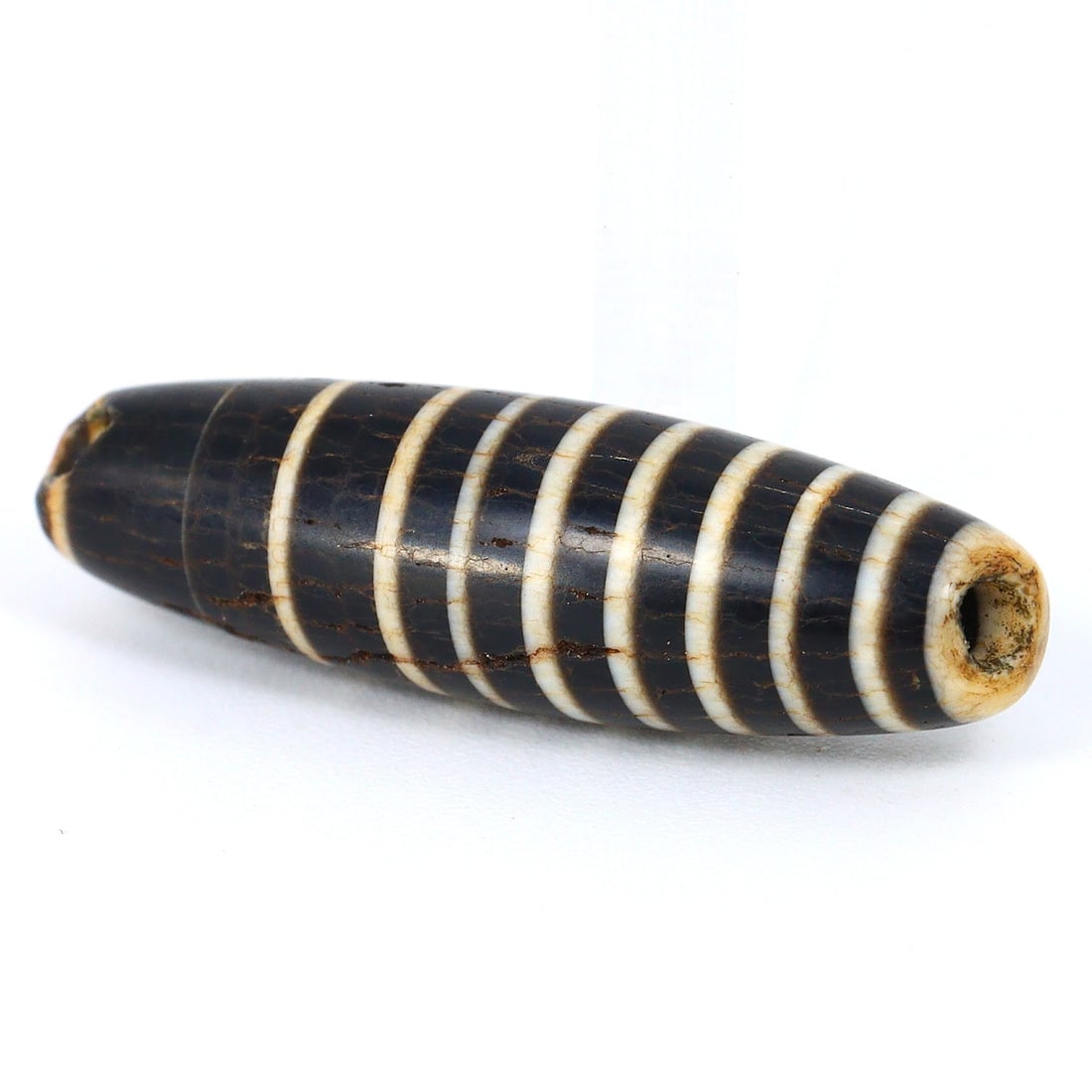 Ancient Sulemani Banded Agate Dzi Bead - Tibetan Silk Road Elegance Unearthed (800-500 BC): Dimension: 20x6 mm Introduction: Embark on a historic journey with this ancient Sulemani banded agate bead, a gem that once traversed the Silk Road between 800 and 500 BC. Meticulously crafted, it enc