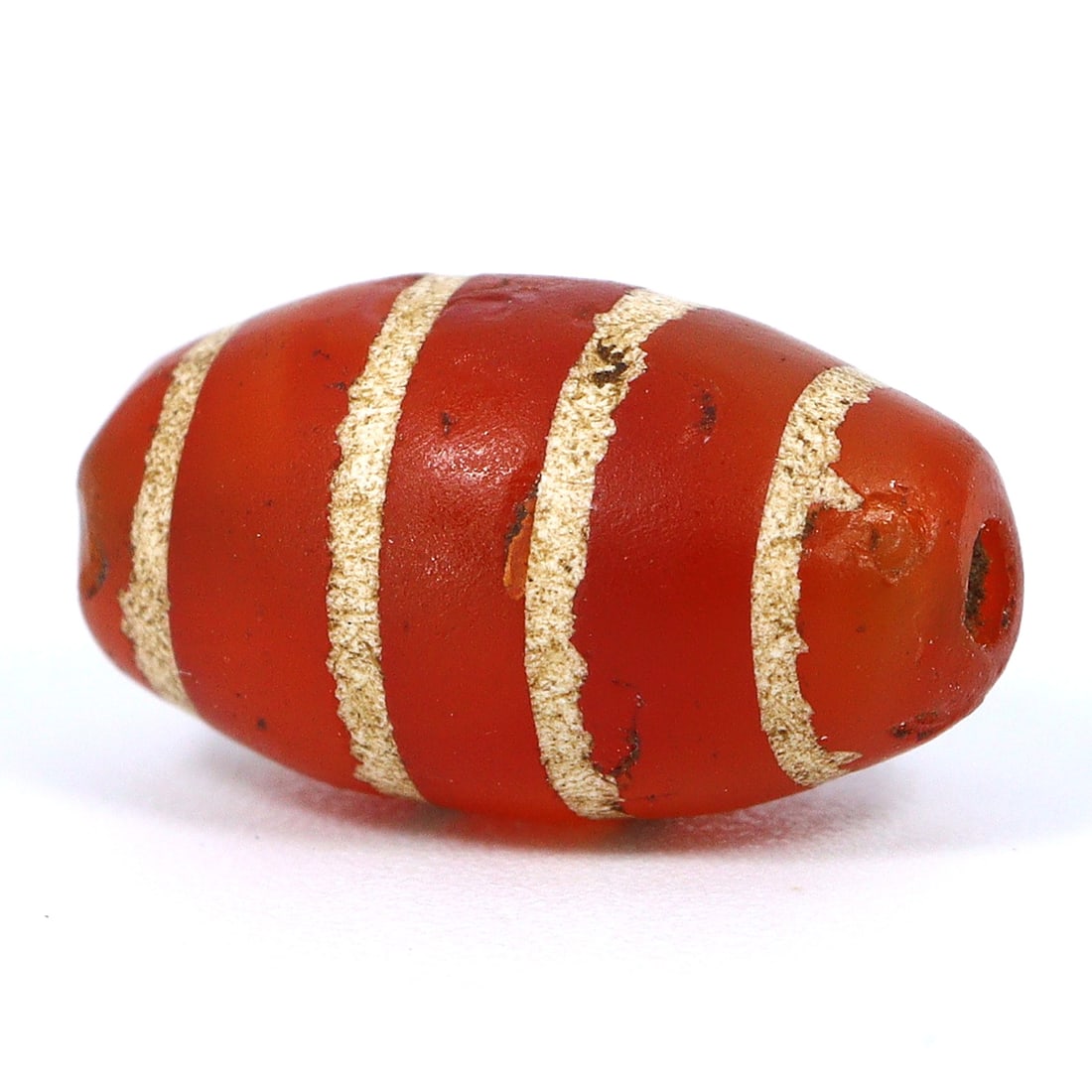 Ancient Etched 4 Stripes Carnelian Bead: Testament to Silk Route Craftsmanship (Medieval Period): Dimension: 11x6mm Rarity Level: Highly Rare Originating from the Silk Route area, especially the Tibetan/Himalayan regions, this etched carnelian bead serves as a testament to the rich trade and cultu