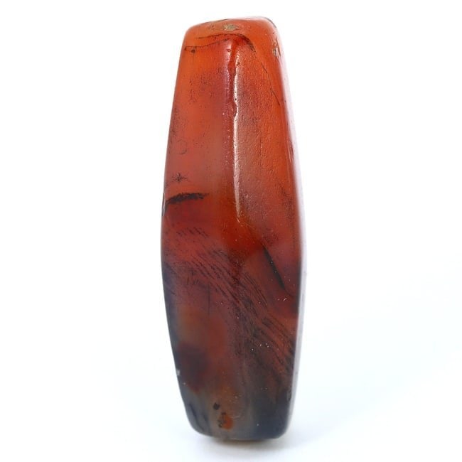 Ancient Bactrian Carnelian Bead - Emblem of Timeless Elegance (1500-1600 BC): Dimension: 20x7mm Introduction: Behold the subtle magnificence of the Ancient Bactrian era with this polished carnelian bead, dated back to 1500-1600 BC. Its warm hues and smooth contours harken to a 