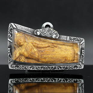 Sculpted Reclining Buddha Amulet in Silver-Tone Casing - Thonburi Era Detailing: This Thai Buddhist amulet, encased in an exquisitely carved locket, spans 6x3.5 cm (2.36x1.38 inches). The amulet portrays the reclining Buddha, a motif rich with meaning, symbolizing the Buddha's fin