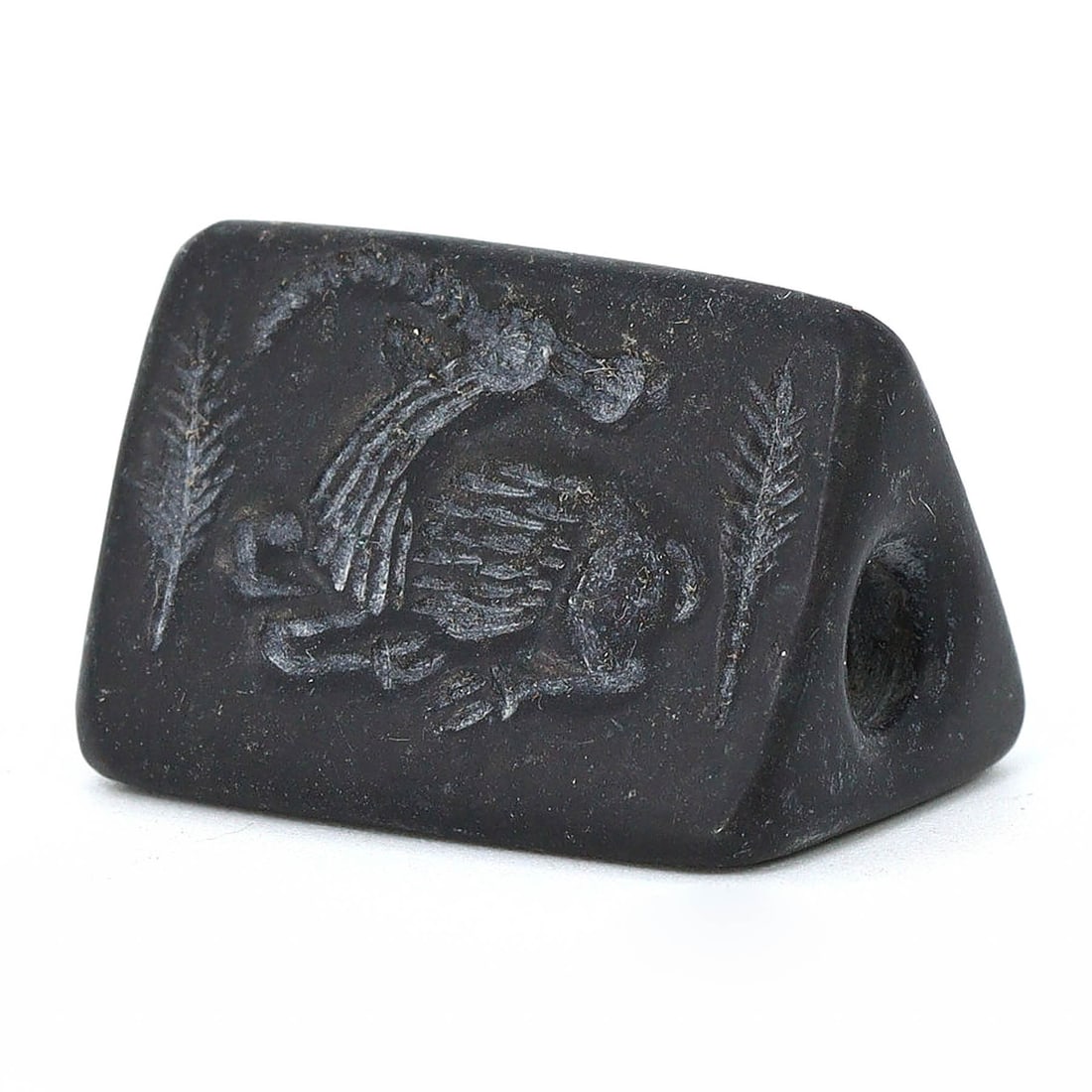 Achaemenid Empire Triangular Stone Seal with Mythical Beasts, Circa 550-330 BC: This black stone seal, sized 2.5x1.5 cm, is adorned with the images of an ibex, lion, and winged lamassu, each face depicting the power and mythology central to the Achaemenid Empire from 550-330 BC. 