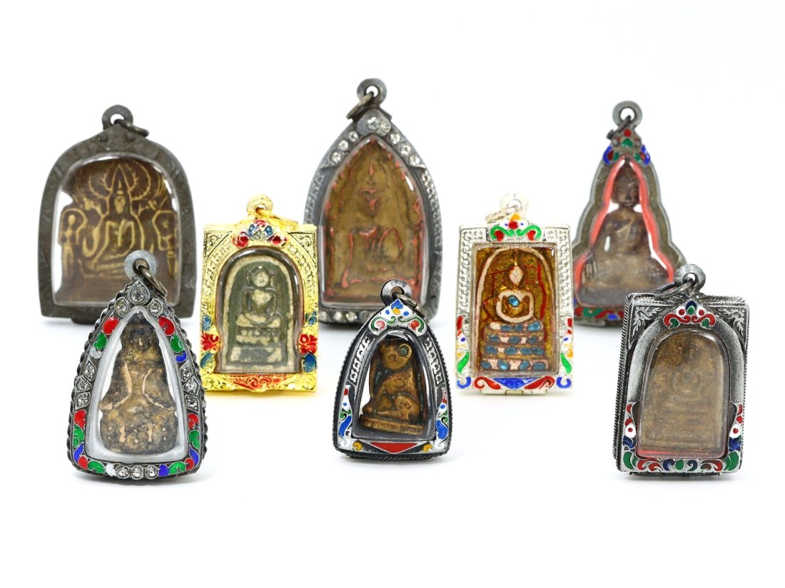 Group of 8 Antique Thai Terracotta Amulets in Vintage Casings: Contained within this lot are eight antique Thai amulets, each enshrined in vintage Thai casings, with the largest amulet measuring 7 cm x 4 cm. These amulets, crafted from terracotta, are embodiments