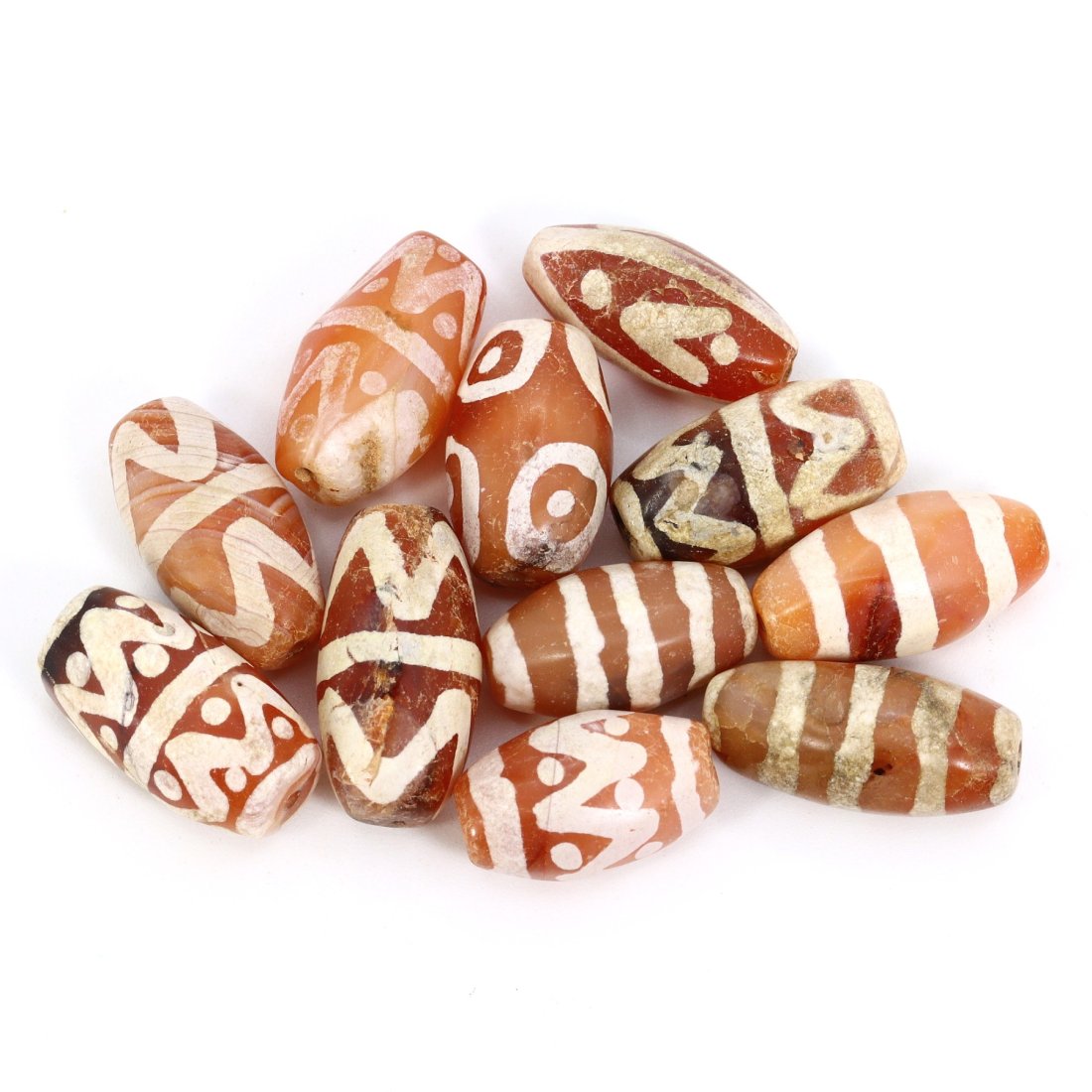 Group of 11 Medieval Himalayan Silk Road Tibetan Etched Carnelian Dzi Beads (6th-17th Century AD): These 11 remarkable Tibetan etched carnelian dzi beads are a testament to the rich history of the Himalayan Silk Road during the Medieval era (6th-17th Century AD). Ranging in dimension from 15mm to 1