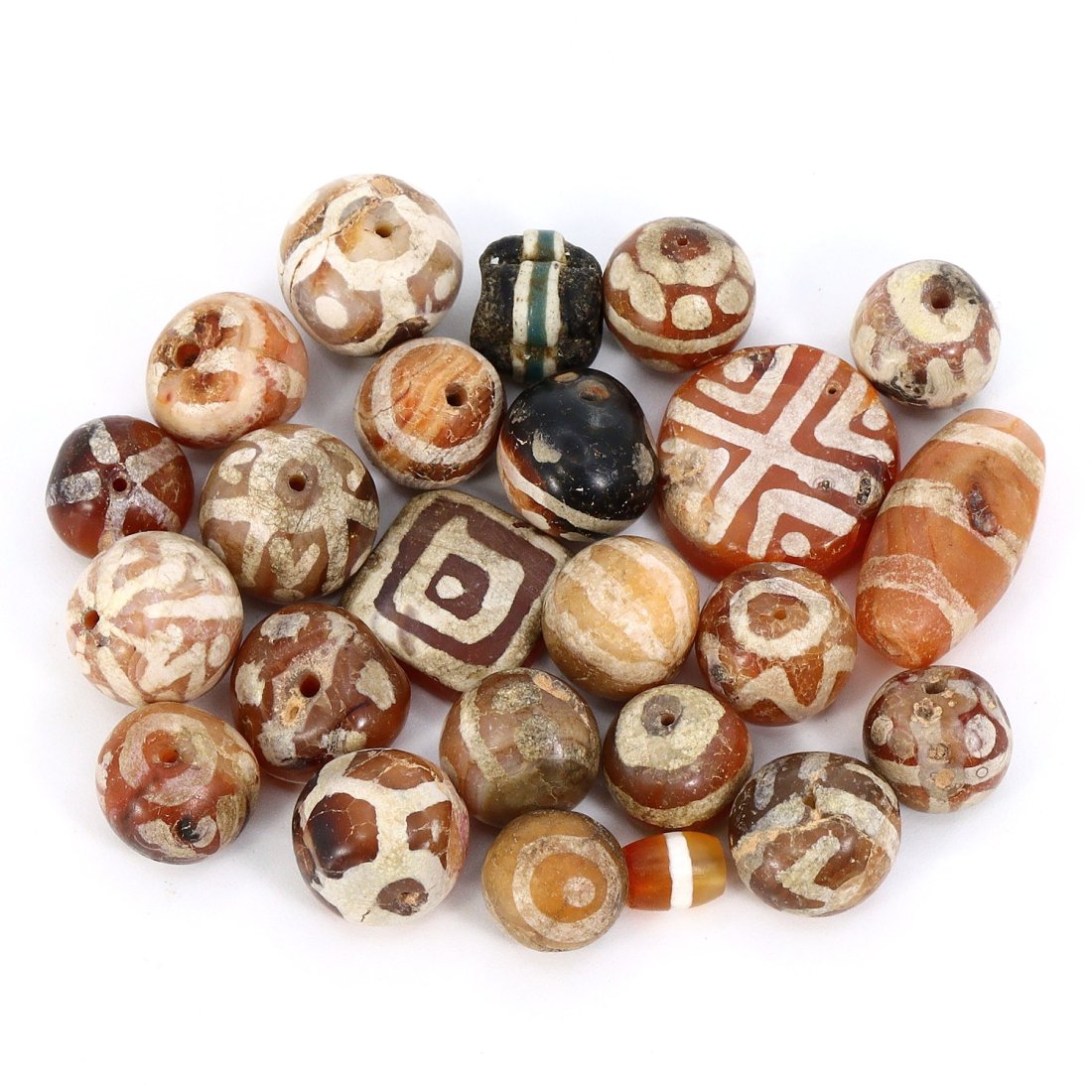 Group of 24 Medieval Himalayan Silk Road Tibetan Etched Carnelian Dzi Beads (6th-17th Century AD): These remarkable Tibetan etched carnelian dzi beads, totaling 24 in number, offer a captivating glimpse into the history of the Himalayan Silk Road during the period spanning from the 6th to the 17th 
