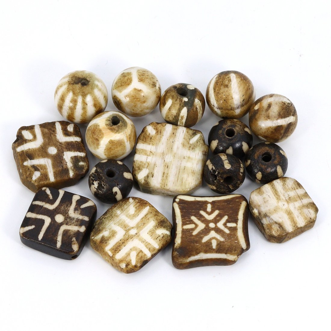 Group of 16 Burmese Phumtek Etched Palm Wood Amulets (1000-1500 AD): This collection comprises 16 palm wood amulets from the Phumtek region of Burma, each meticulously etched with geometric designs. They range in size from 12-22mm, embodying the distinctive craftsmansh
