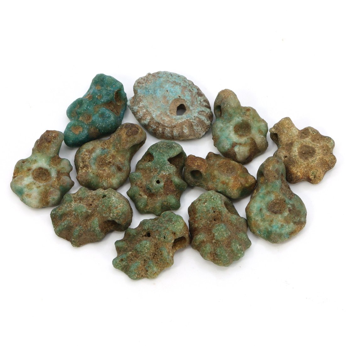 Group of 12 Egyptian Faience Amulets in Eye and Sun Forms (664-332 BC): This unique collection consists of 12 faience amulets from ancient Egypt, each one intricately crafted into symbolic forms of eyes and suns, ranging in size from 20-24mm. The use of faience, a glazed 
