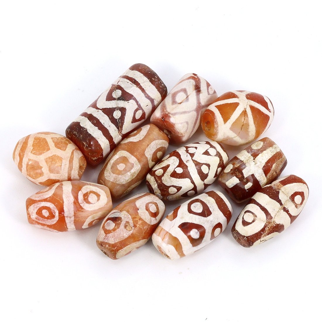 Group of 11 Medieval Himalayan Silk Road Tibetan Etched Carnelian Dzi Beads (6th-17th Century AD): These 11 remarkable Tibetan etched carnelian dzi beads are a testament to the rich history of the Himalayan Silk Road during the Medieval era (6th-17th Century AD). Ranging in dimension from 14mm to 2