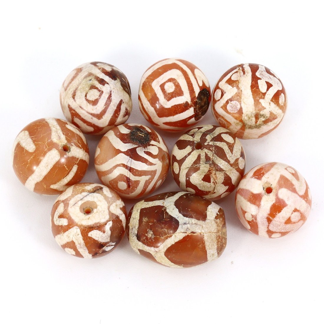 Group of 9 Medieval Himalayan Silk Road Tibetan Etched Carnelian Dzi Beads (6th-17th Century AD): These 9 remarkable Tibetan etched carnelian dzi beads are a testament to the rich history of the Himalayan Silk Road during the Medieval era (6th-17th Century AD). Ranging in dimension from 10mm to 11