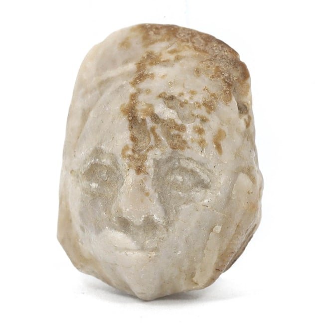 Western Asiatic Man's Face Anthropomorphic Carving (1000 BC-100 AD): This diminutive anthropomorphic carving depicts the face of a man and hails from the Classical Antiquities period of Western Asia. With dimensions of roughly 0.79x0.59x0.39 inches (2x1.5x1 cm), the in