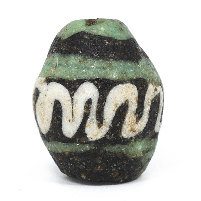 Islamic Art Egyptian Glass Bead with Trail Pattern, 9th-12th Century AD: This ancient glass bead, with its distinctive trail pattern, is a fine example of Islamic art from Egypt, likely produced between the 9th and 12th centuries AD. The bead measures 1.7x1.3 cm and featur