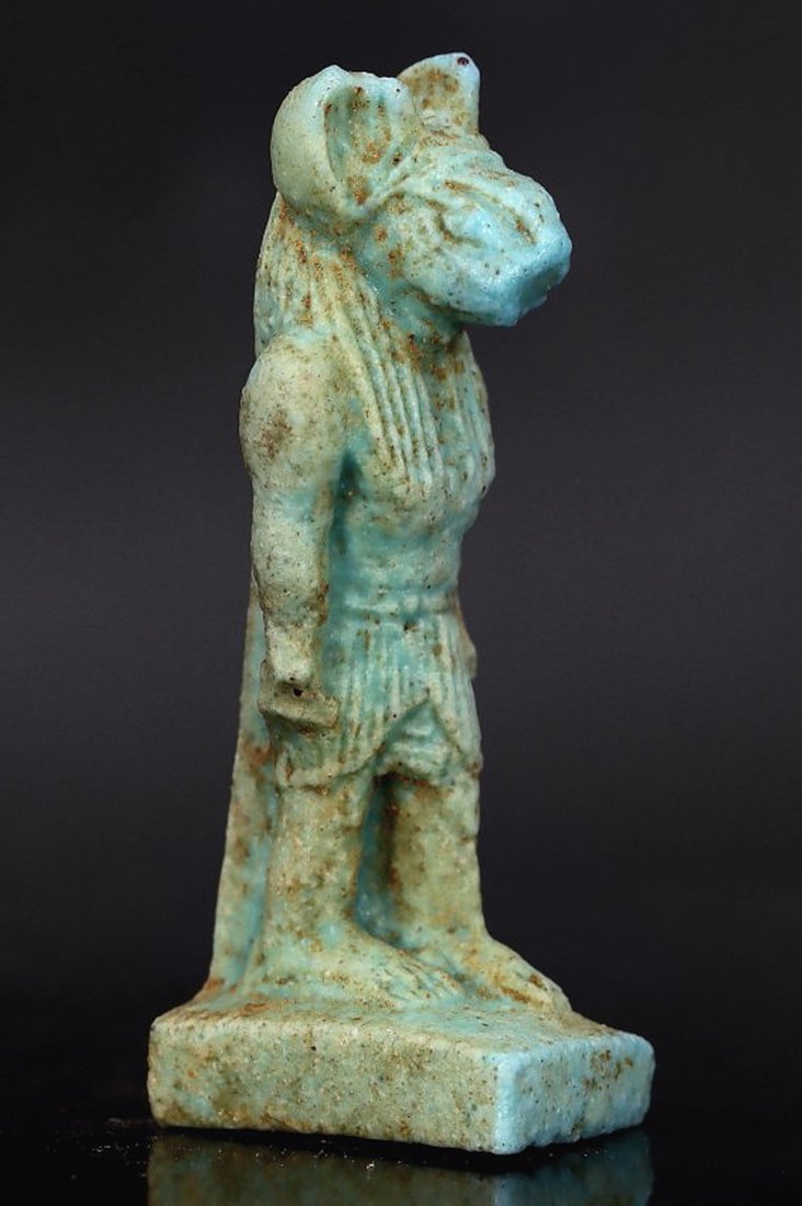Ancient Egyptian Faience Figurine of Sekhmet (1300-1100 BC): This Egyptian figurine represents Sekhmet, the lioness-headed goddess associated with war and healing, measuring 4.5x1.5x1 cm (1.77x0.59x0.39 inches). Made from faience, a material esteemed for its gl