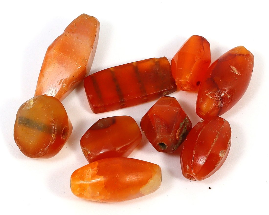 Late Ancient to Islamic Egyptian Carnelian Beads, 7th-12th Century AD: A collection of nine carnelian beads and amulets span the transition from Late Ancient Egypt to the Islamic period, specifically from the 7th to the 12th century AD. These beads, ranging in size from 