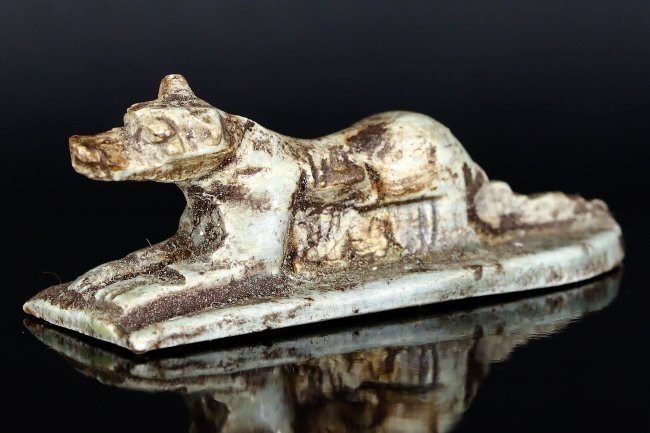A Glazed Steatite Amulet of Anubis, Late Period, 664-332 BC: This exquisitely crafted glazed steatite amulet represents Anubis, the jackal-headed god associated with mummification and the afterlife in ancient Egyptian religion. Lying down on a rectangular base,
