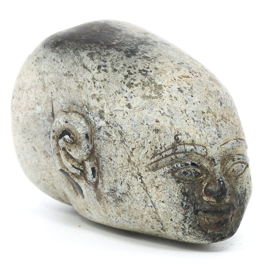A Ptolemaic Period Carved Stone Head Fragment: This stone head fragment, measuring 6.5 cm at its greatest extent, is a remarkable piece dating back to the Ptolemaic Period, an era marked by the fusion of Greek and Egyptian art forms. The sculpted