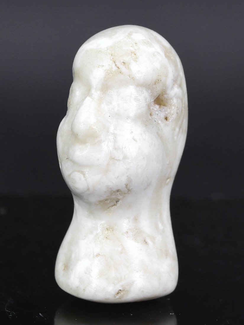 A Greco-Bactrian Alabaster Head, 3rd-2nd Century BCE: This alabaster head sculpture, with dimensions of 3 cm in length, represents the artistry of the Greco-Bactrian period, blending classical Greek styles with eastern influences. The stylized features, 