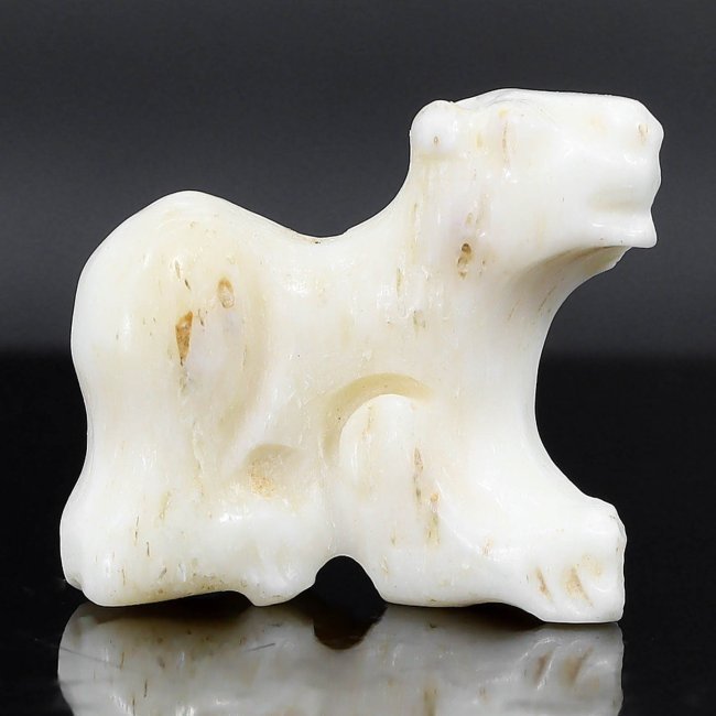 An Ancient Egyptian Bone Canine Amulet, Late Period, c. 664-332 B.C.: An exquisitely carved bone canine amulet from the Late Period of Ancient Egypt, this small artifact captures the essence of a creature revered for its loyalty and protection. Dogs were often depicted 