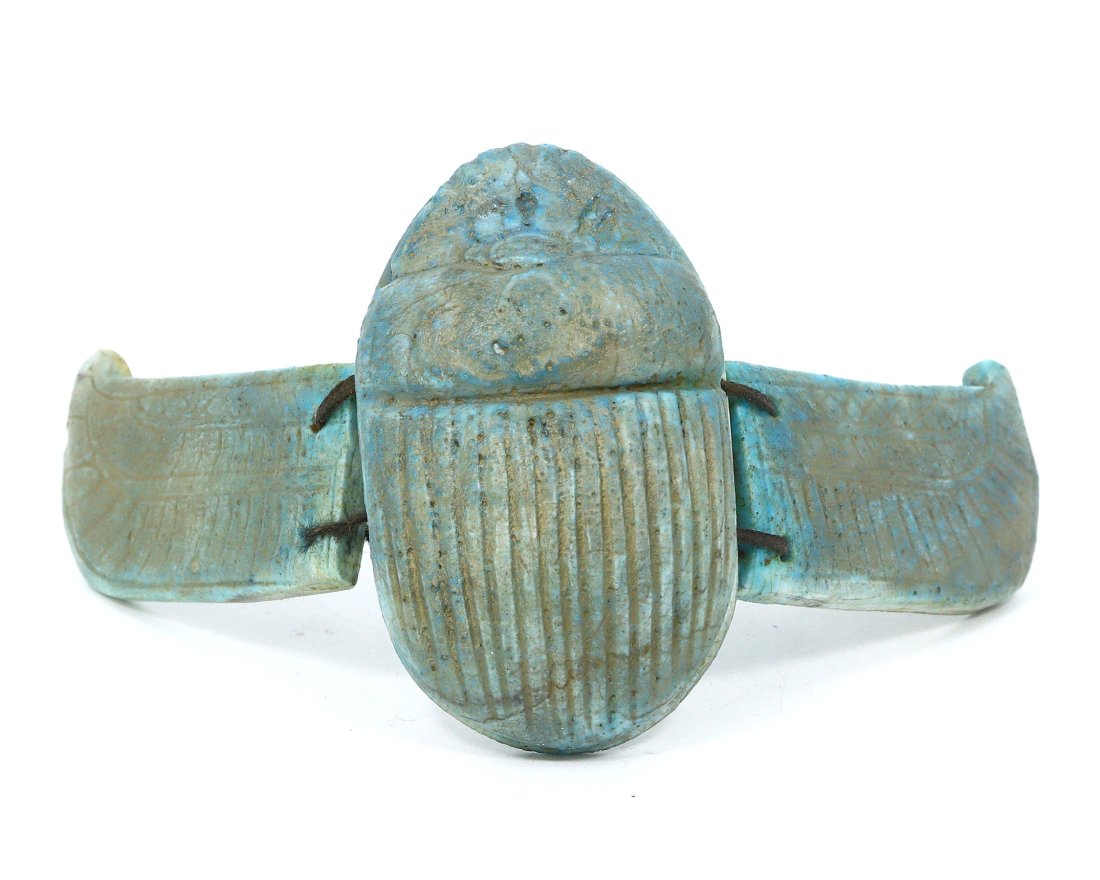 Ancient Egyptian Glazed Steatite Winged Scarab, New Kingdom 1570-1070 BC: This winged scarab, exquisitely crafted from glazed steatite, features the traditional Egyptian blue symbolic of the heavens. The artistry is evident in the detailed wings and hieroglyphic patterns, i