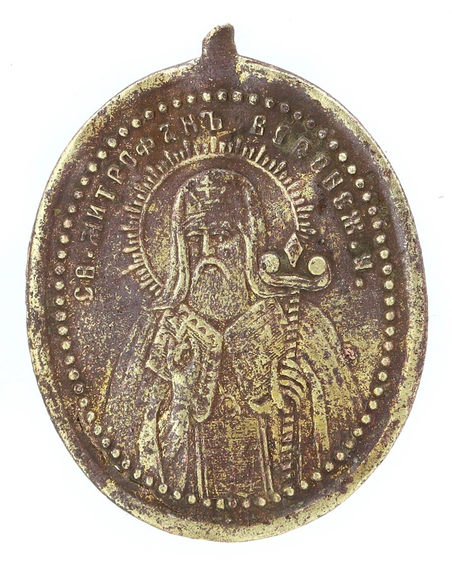 Byzantine Bronze Saint Medallion, 8th-10th Century AD: This Byzantine bronze medallion presents the high relief of a revered saint, encircled by a worn inscription. The figure, marked by the characteristic halo, is adorned with elaborate ecclesiastical ve