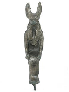 An  Metallic Figurine of the God Anubis: This metallic figurine embodies Anubis, the jackal-headed god associated with mummification and the afterlife in ancient Egyptian religion. Standing at 13.5 cm, its elongated form and the oxidized pat