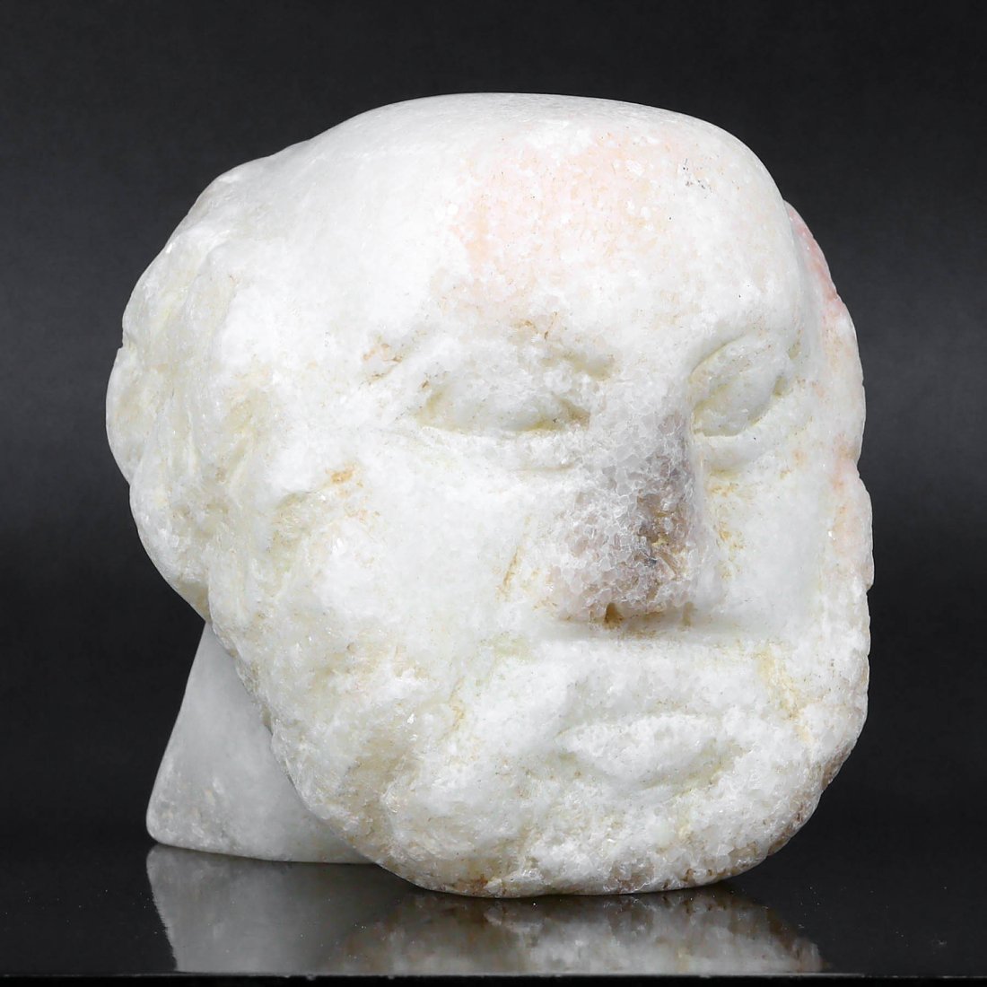 Fragment of a Greco-Roman Marble Head: This exquisite fragment of a marble head reveals the Greco-Roman era's skilled artistry, with remnants of facial features weathered by time. The crystalline structure of the marble glistens subtly, hi
