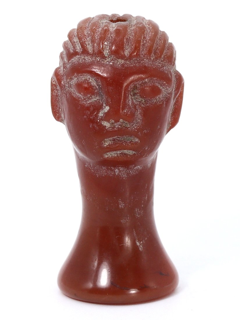 An Ancient Byzantine Coptic Carnelian Head Bead, 4th–7th Century CE: A striking example of Byzantine-era craftsmanship, this carnelian bead is carved in the likeness of a head, featuring stylized facial features distinctive to Coptic Egyptian art. Carnelian, a semi-pre