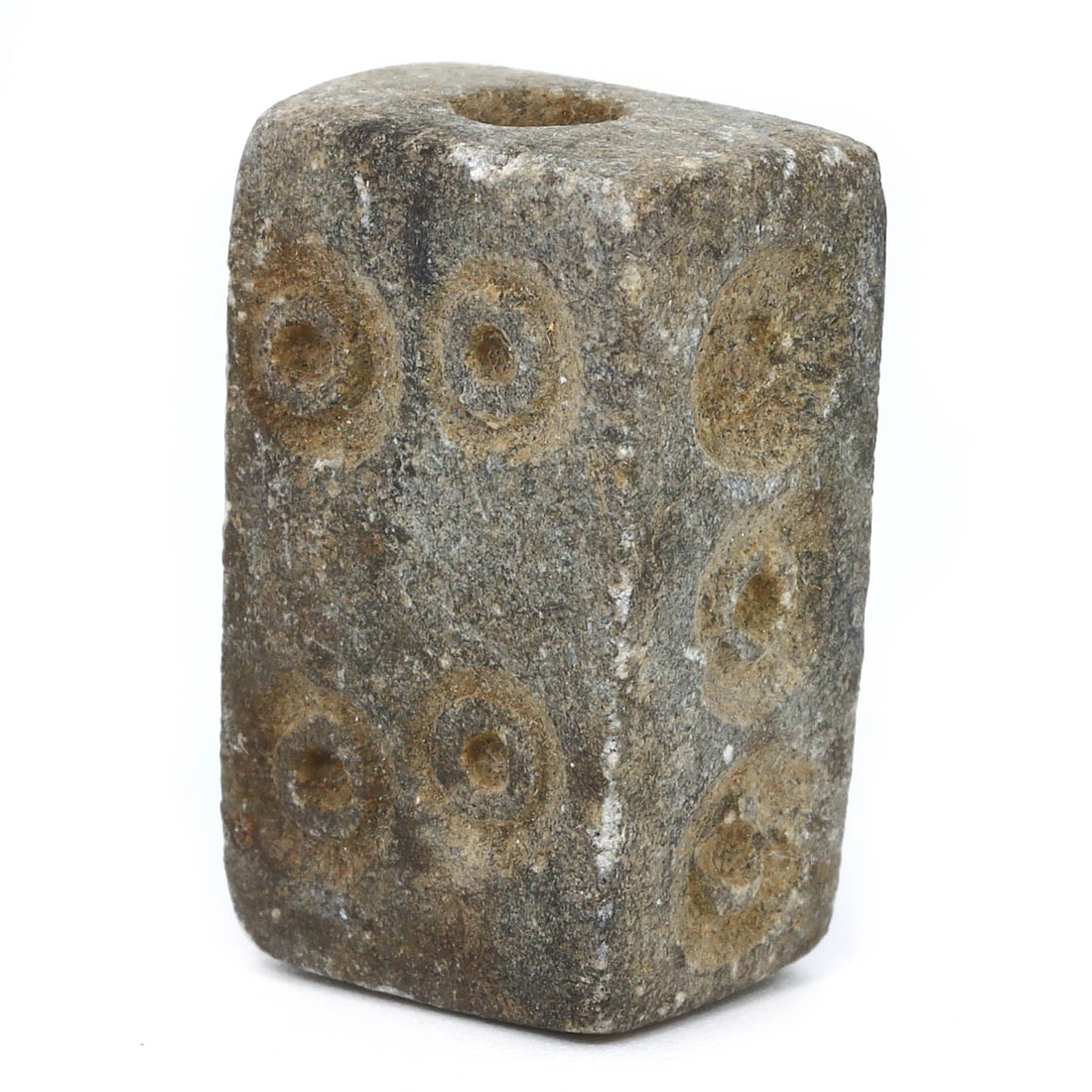 An Ancient Mesopotamian Steatite Dice Bead, Circa 3rd Millennium BCE: This steatite dice bead from ancient Mesopotamia, intricately carved with circular motifs, speaks of the region's advanced culture where such items likely held significance in trade, gaming, or as per