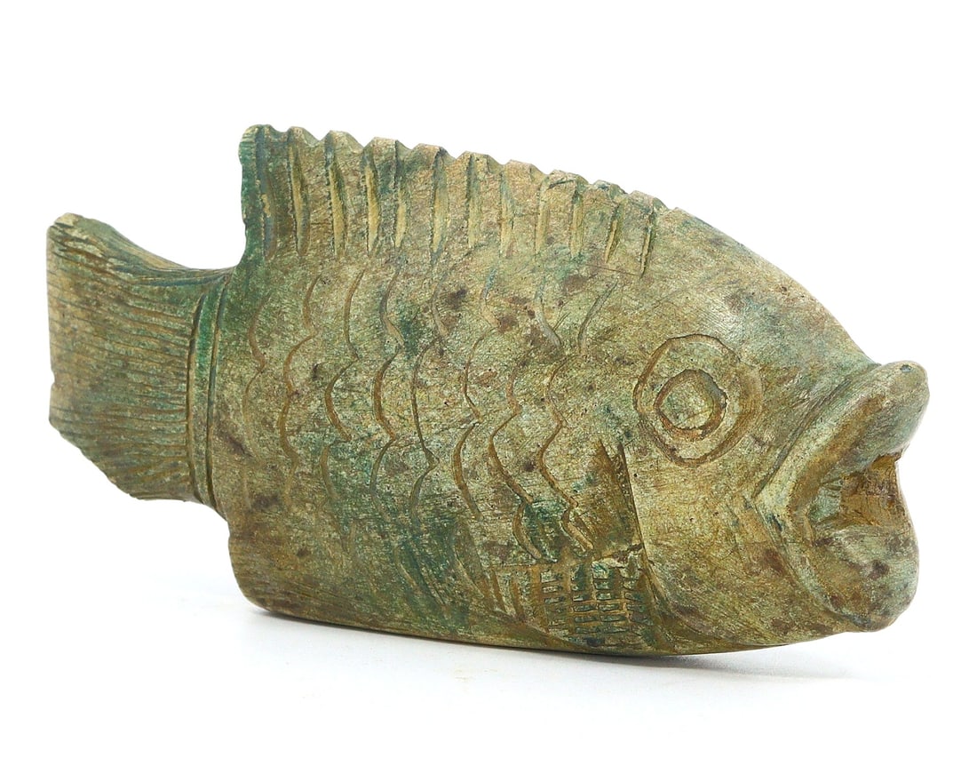 A Glazed Steatite Fish Amulet, Egyptian Revival or Contemporary: This charming steatite amulet, carved in the form of a fish and measuring 8.5 by 4.5 cm, may be a nod to ancient Egyptian symbolism or a contemporary piece inspired by it. The fish is a symbol that ap