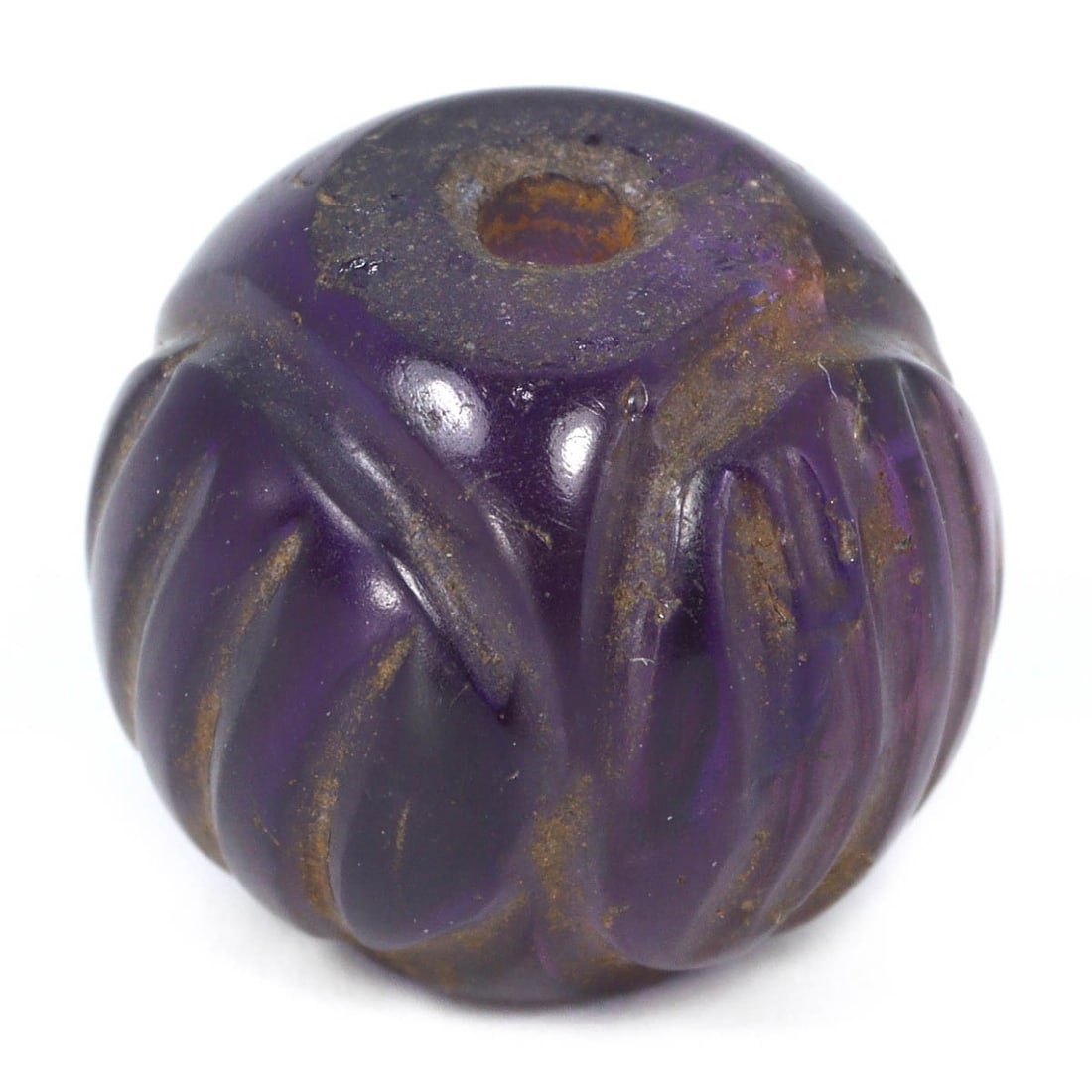 An Antique Mughal Empire Melon-Shaped Amethyst Bead, 16th–19th Century: A distinct South Asian melon-shaped amethyst bead, with a polished surface that accentuates its deep purple hues and natural inclusions. The ribbed melon shape is indicative of the skilled craftsmansh