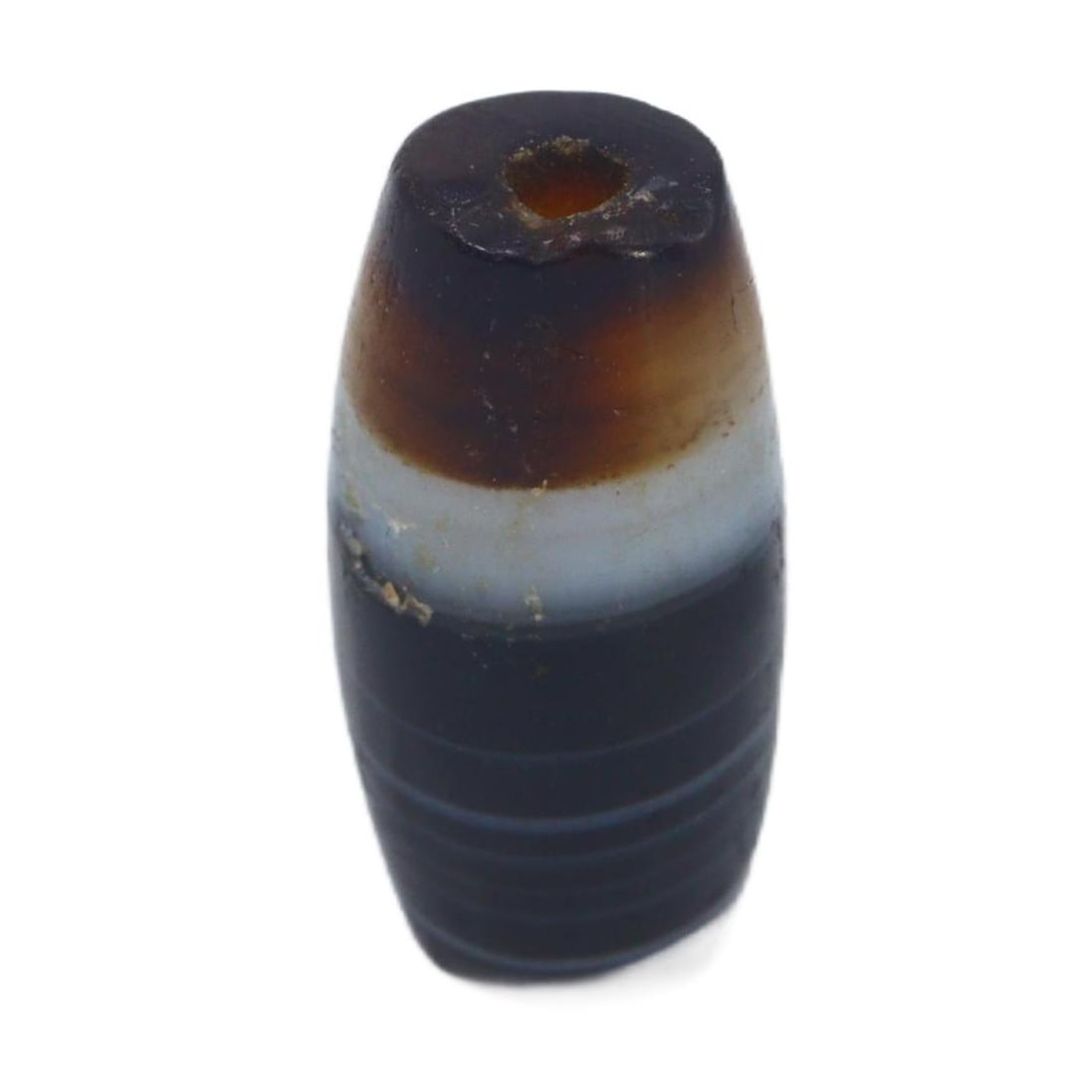 An Ancient Tibetan Banded Agate Chung Dzi Bead, 6th-10th Century AC: This chung dzi bead, with its enigmatic dark hues and stark banding, is a quintessential artifact of Tibetan culture. Dzi beads are deeply rooted in Tibetan tradition, often used as protective amulets