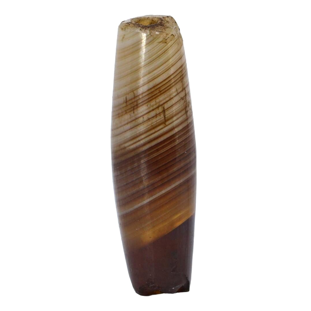 An Antique Silk Road Era Tibetan Dzi Bead, 11th-16th Century: This Dzi bead, marked by its length and the wavy, flowing bands reminiscent of the agate's natural layering, speaks to its origin along the ancient Silk Road. Prized for millennia, Dzi beads are rever