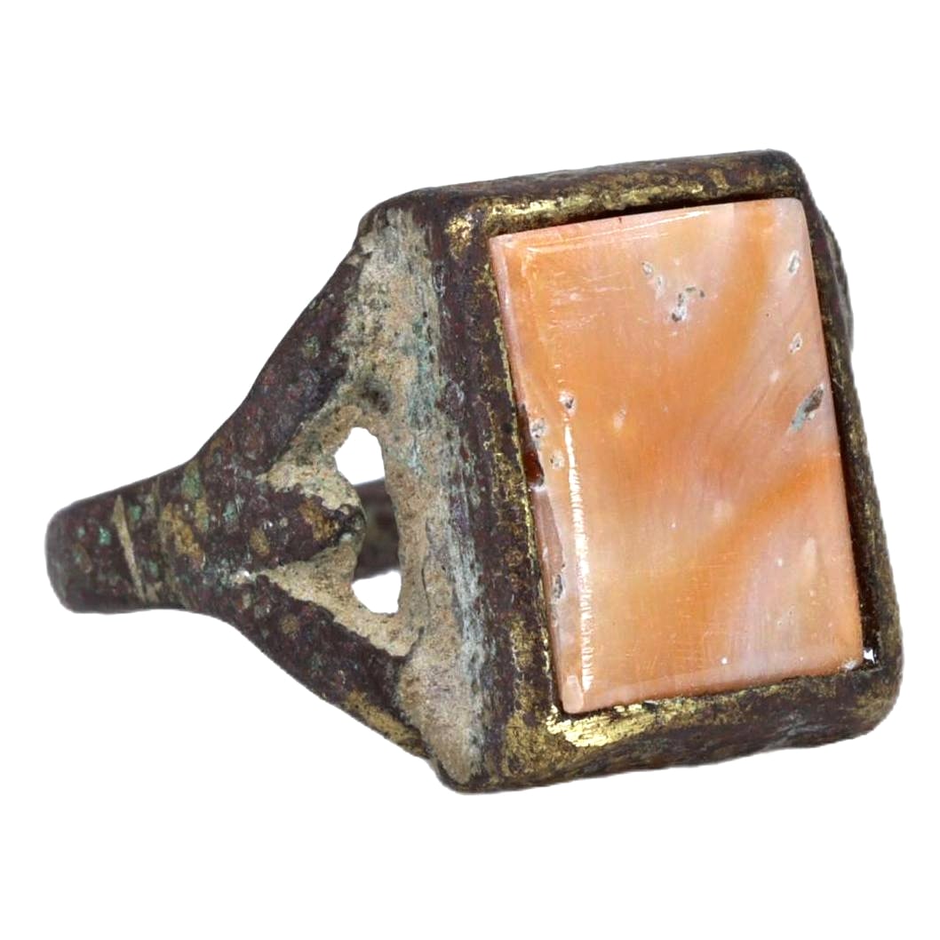 An Antique Silver Ring with Coral Inlay, ca. 10th-12th Century CE: Category: Bracelets and Armlets This ring features a prominent coral inlay, set in a finely crafted silver band. The use of coral as ornamentation is notable in various ancient cultures and often symb