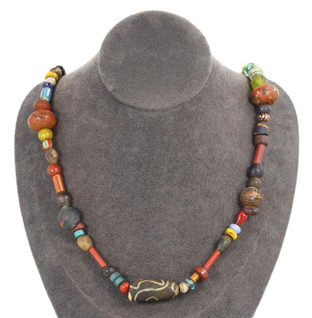 Antique Bead Necklace with Global Trade Beads, Early to Mid 20th Century: This necklace is a celebration of global beadwork, featuring an eclectic mix of antique beads from various cultures, popular in the early to mid 20th century. It includes elements like African trade b