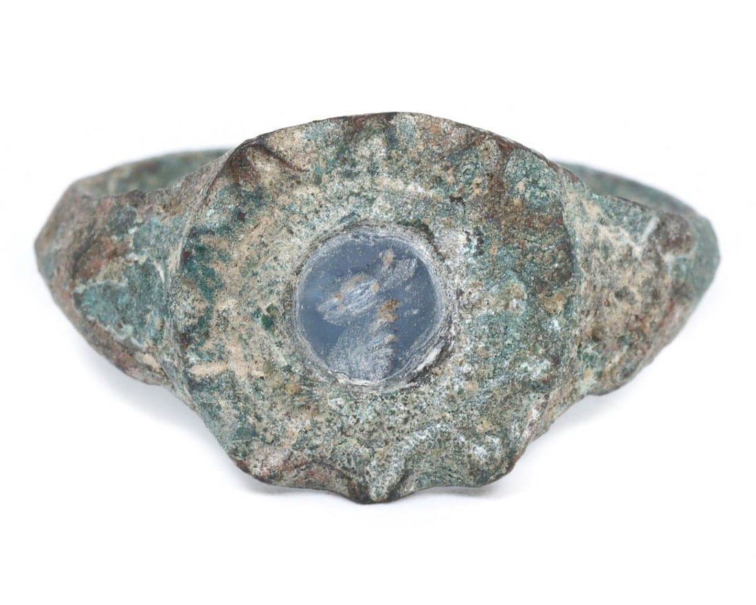 An Ancient Semi-Precious Bronze Signet Ring, Sasanian Empire, c. 224-651 CE: This ancient Sasanian bronze signet ring features a semi-precious stone intaglio, exquisitely preserved within a heavily patinated bronze setting. The intaglio, possibly sapphire, depicts celestial mo