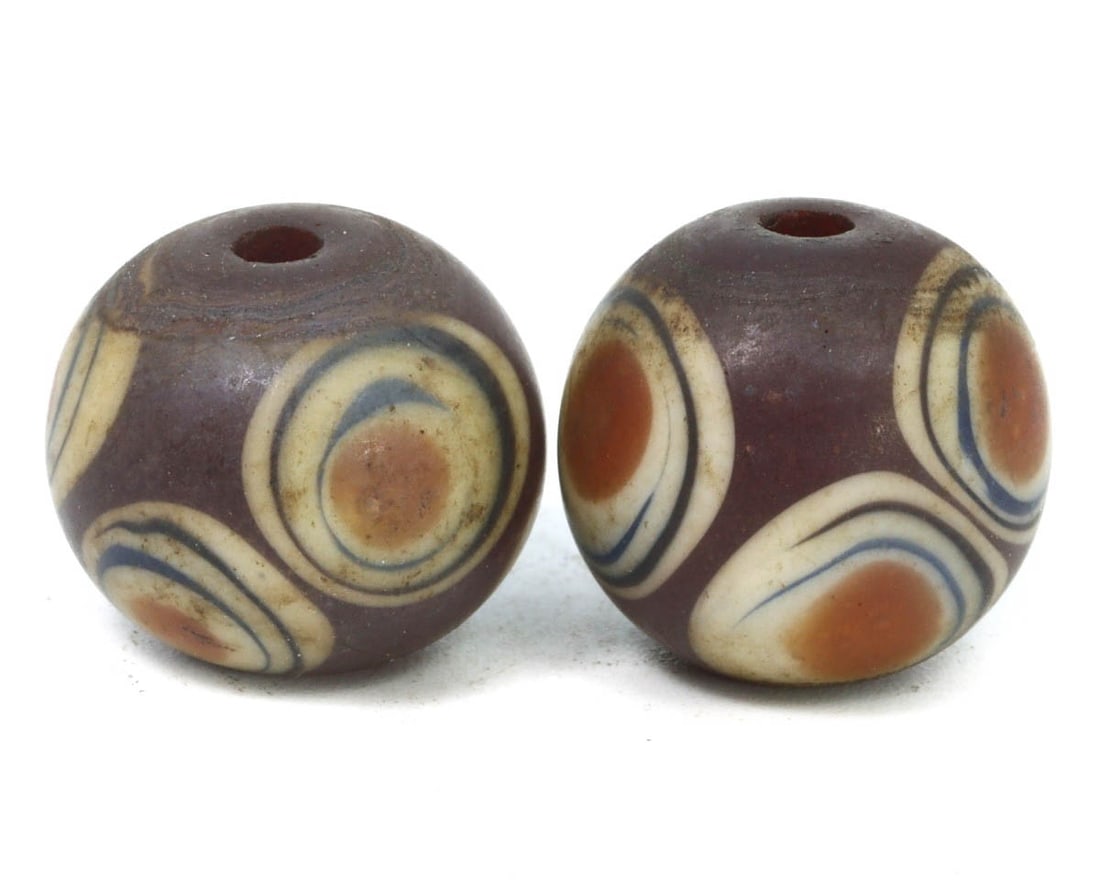 A Pair of Ancient Islamic Eye Glass Beads, c. 8th-10th Century CE: These two ancient Islamic glass beads, adorned with eye motifs, are exemplary of the sophisticated glass-making techniques from the 8th to 10th centuries CE. The design, featuring concentric circles i
