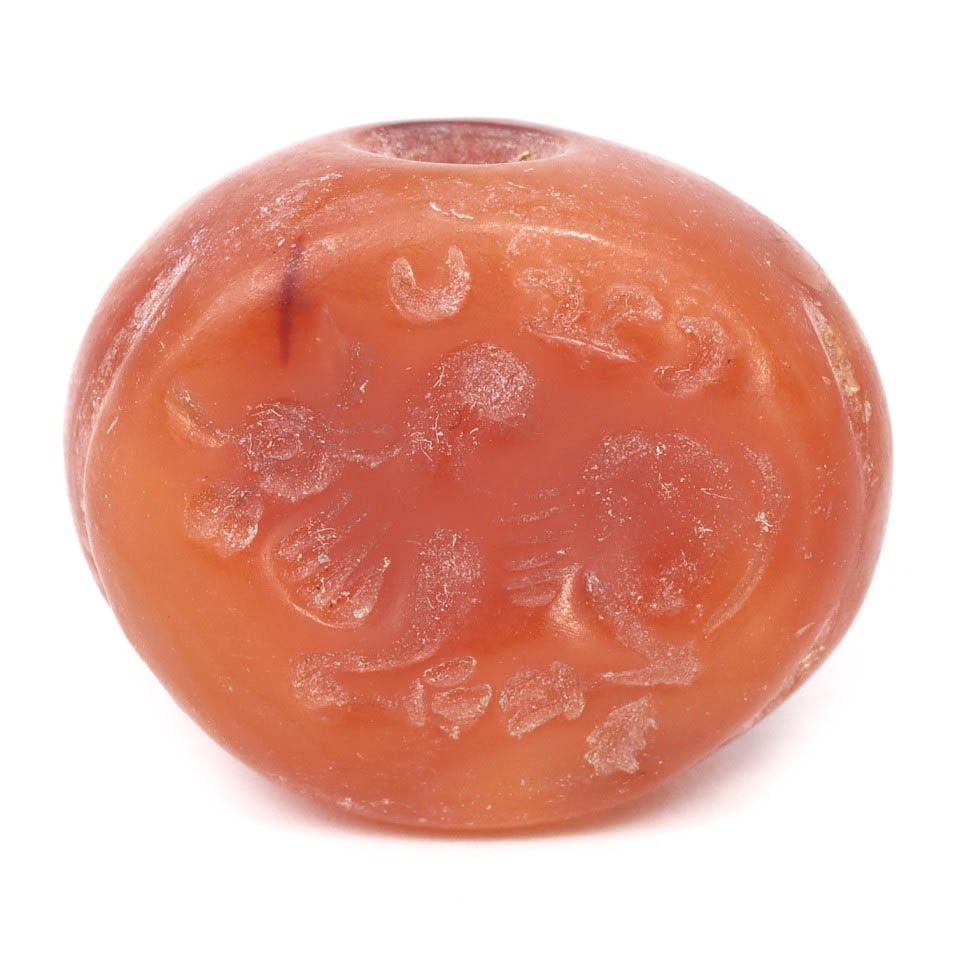 An Ancient Sasanian Carnelian Hemispherical Stamp Seal, c. 224-651 CE: This hemispherical stamp seal, carved from carnelian, dates back to the Sasanian period, circa 224-651 CE. The seal displays intricate carvings that illustrate the artistic and cultural significance o