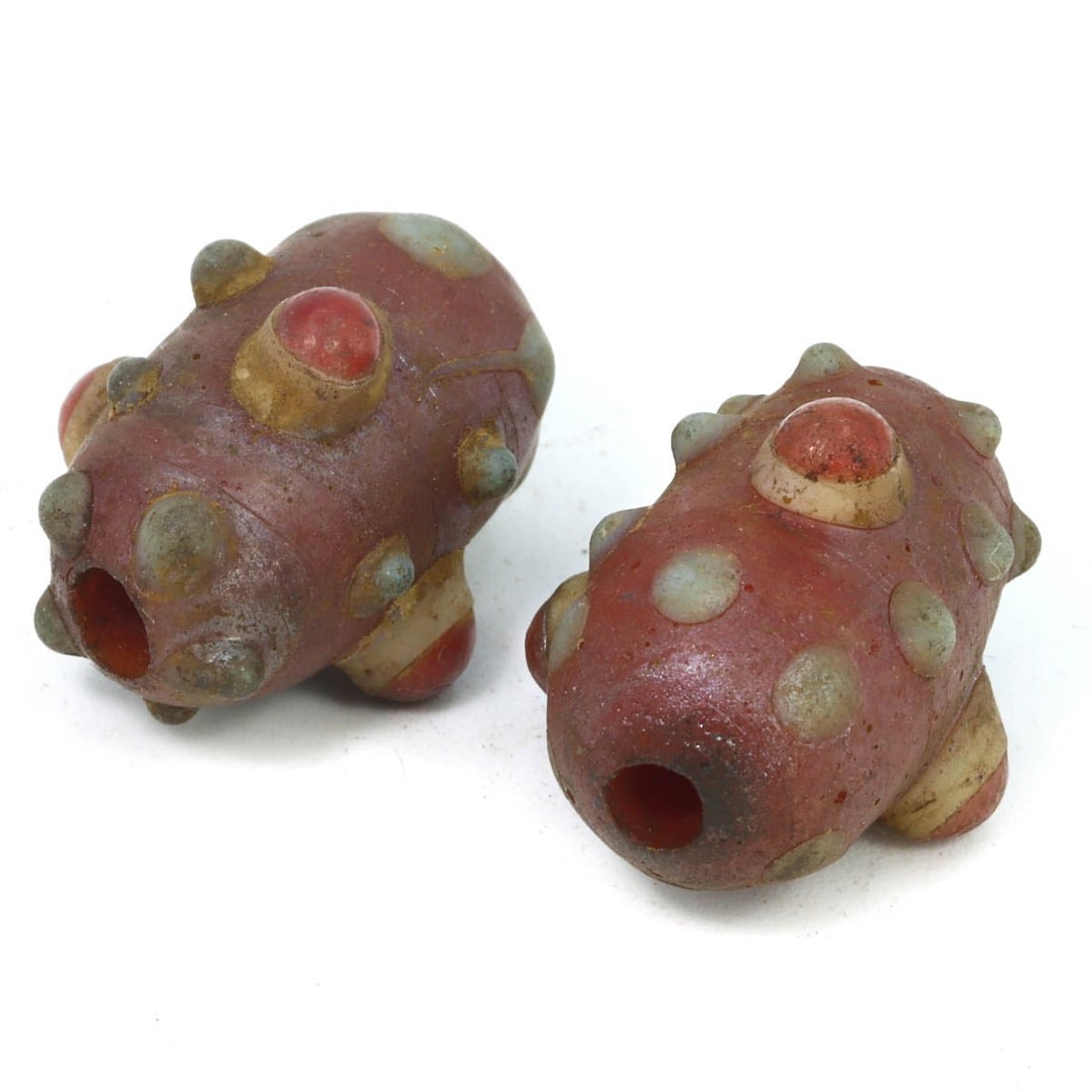 Pair of Ancient Byzantine-Islamic Wound Glass Eye Beads, c. 600-900 AD: This pair of eye beads, made from celadon, warming peach, and caramelized wound glass. Dating back to the Byzantine-Islamic period (c. 600-900 AD), it exemplifies the intricate craftsmanship and vibra