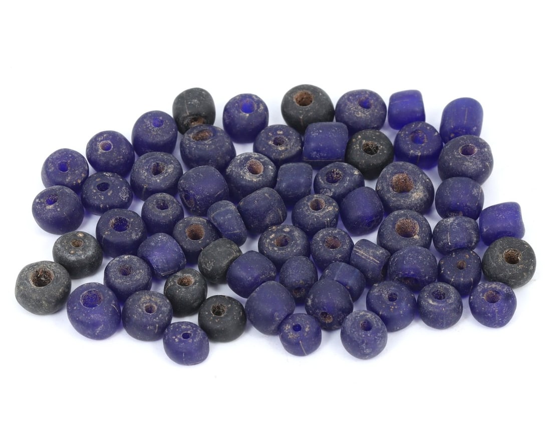 An Antique Medieval Glass Collection of Beads, c. 1000-1300 AD: This exquisite collection of beads, made from purple, indigo, and cobalt glass, showcases a variety of mixed shapes. Dating back to the Medieval period (c. 1000-1300 AD), it exemplifies the skilled cr