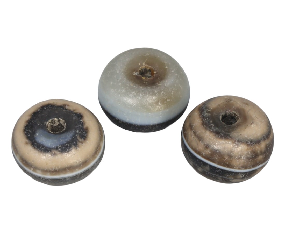 An Ancient Sulemani Luk Mik Goat Eye Agate Bead, 7th-12th Century: This Sulemani Luk Mik Goat Eye bead exemplifies the intricate agate beadwork from the height of the Silk Road's significance. Its creamy beige and transparent stripes, culminating in a central "eye," 