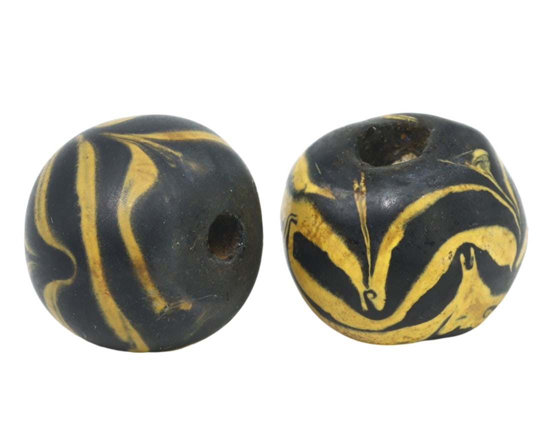 Lot of Antique Islamic Glass Beads, c. 9th-10th Century: This pair of trailed, wound beads, made from wond glass with mosaic glass insets. Dating back to the Islamic Golden Age (c. 9th-10th Century), it exemplifies the intricate craftsmanship and artistic i